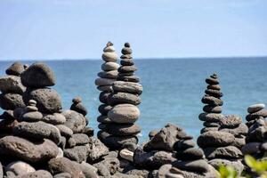 a stack of rocks on the beach by the ocean photo