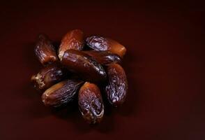 Several ripe dates on a dark red background. Delicious dates on red. photo