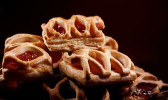 Puff pastry pastry with lingonberry jam on a dark red background. Cookies with lingonberry jam. photo