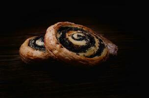 Two delicious buns with poppy seeds on a dark background. photo