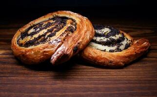 Two delicious buns with poppy seeds lie on a wooden background. photo