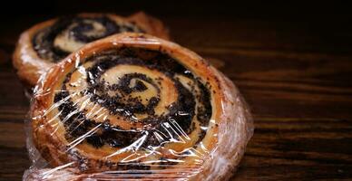 Two poppy seed buns wrapped in plastic wrap. photo