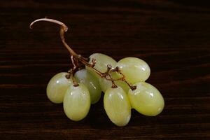 Small bunch of ripe green grapes on a wooden background. photo