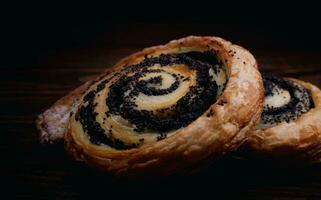Two delicious buns with poppy seeds on a dark background. photo
