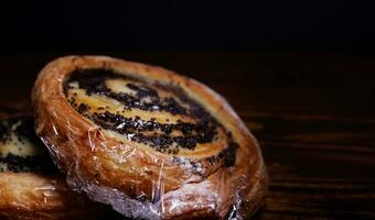 Two poppy seed buns wrapped in plastic wrap. photo