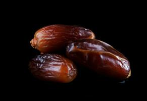 Several ripe dates on a black background. Delicious dates on black. photo