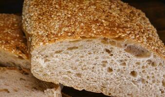 Cut loaf of bread and pieces of bread on a wooden background. Ciabatta bread. photo