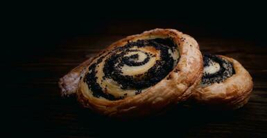 Two delicious buns with poppy seeds on a dark background. photo