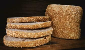 Cut loaf of bread and pieces of bread on a wooden background. Ciabatta bread. photo