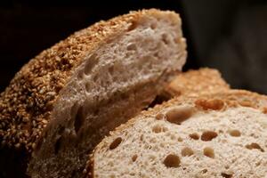 Cut loaf of bread and pieces of bread on a wooden background. Ciabatta bread. photo