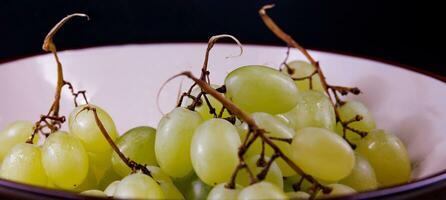 A small beautiful bunch of ripe green grapes in a deep ceramic plate. photo