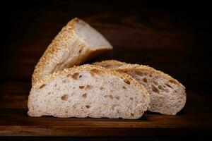 Cut loaf of bread and pieces of bread on a wooden background. Ciabatta bread. photo