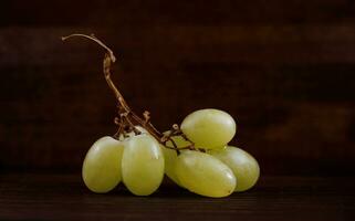 Small bunch of ripe green grapes on a wooden background. photo