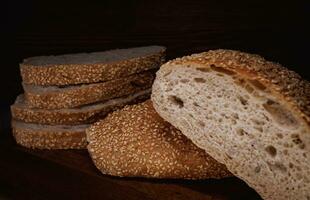 Cut loaf of bread and pieces of bread on a wooden background. Ciabatta bread. photo