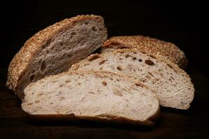 Cut loaf of bread and pieces of bread on a wooden background. Ciabatta bread. photo