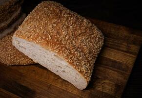 Cut loaf of bread and pieces of bread on a wooden background. Ciabatta bread. photo