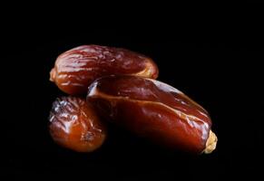 Several ripe dates on a black background. Delicious dates on black. photo