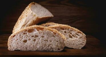 Cut loaf of bread and pieces of bread on a wooden background. Ciabatta bread. photo