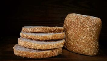 Cut loaf of bread and pieces of bread on a wooden background. Ciabatta bread. photo