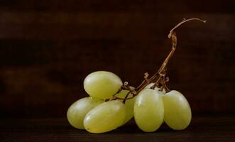 Small bunch of ripe green grapes on a wooden background. photo