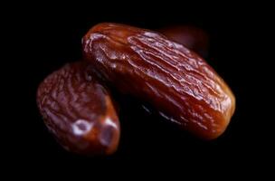 Several ripe dates on a black background. Delicious dates on black. photo