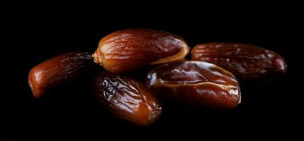 Several ripe dates on a black background. Delicious dates on black. photo