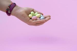 huevos de codorniz de color natural en una mano femenina sobre un fondo rosa. bandera. de cerca foto