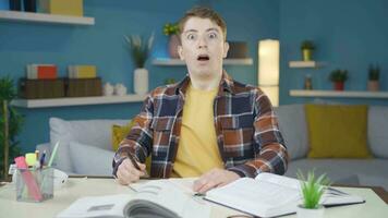 Young student doing homework looks at camera in amazement. video