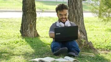 Universidad enano estudiante chateando en ordenador portátil al aire libre en parque. video