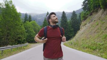 Happy young man walking on asphalt road in forest. video