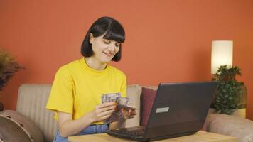 mujer mirando a ordenador portátil contando dinero. video