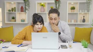 The couple reacting negatively to what they see on the laptop. video