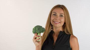 Cheerful healthy beautiful woman holding broccoli, showing thumbs up video