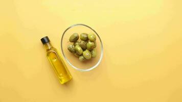 bottle of olive oil and fresh olive in a container on table . video