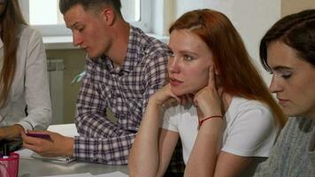 Red haired woman looking annoyed while working on a project at school video