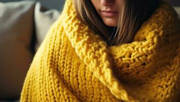 Close up of a young woman wrapped in a yellow knitted blanket AI Generated photo