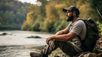 Handsome bearded man sitting on a rock near the river. AI Generated. photo