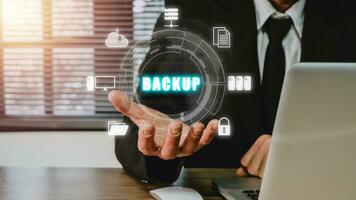 Backup storage data internet technology business concept, Businessman using a computer and hand holding VR screen backup icon on desk. photo