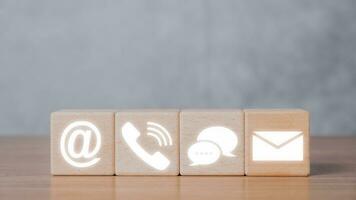 Contact us or Customer support hotline people connect, Wooden blocks with contact us icon on dark background. photo