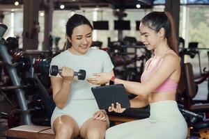 joven mujer y un personal entrenador con pesa peso formación a el gimnasia. foto