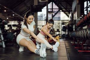 aptitud física, extensión y dos mujer a gimnasio para un calentar arriba ejercicio, formación y cuerpo bienestar con ejercicio. joven Deportes hembra o atleta en piso a tramo piernas para fuerte músculo, equilibrar y energía. foto