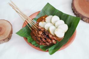 chicken satay on a white plate with peanut sauce photo