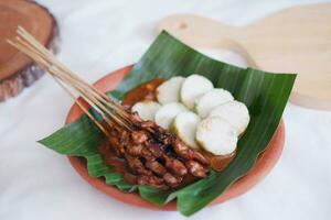 chicken satay on a white plate with peanut sauce photo