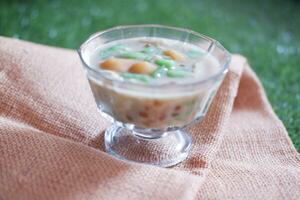 coconut milk in small glass on green grass background photo