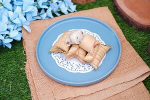 Lepet or Leupeut is a type of snack made from glutinous rice mixed with peanuts, cooked in coconut milk, then wrapped in coconut leaves. Close up view photo