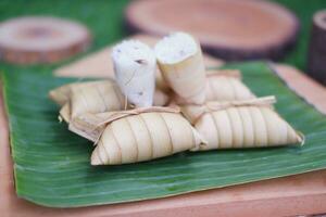 Lepet or Leupeut is a type of snack made from glutinous rice mixed with peanuts, cooked in coconut milk, then wrapped in coconut leaves. Close up view photo
