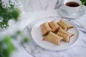 Lepet or Leupeut is a type of snack made from glutinous rice mixed with peanuts, cooked in coconut milk, then wrapped in coconut leaves. Close up view photo