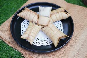 Lepet or Leupeut is a type of snack made from glutinous rice mixed with peanuts, cooked in coconut milk, then wrapped in coconut leaves. Close up view photo