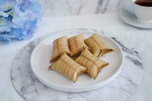 Lepet or Leupeut is a type of snack made from glutinous rice mixed with peanuts, cooked in coconut milk, then wrapped in coconut leaves. Close up view photo