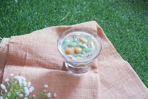 coconut milk in small glass on green grass background photo